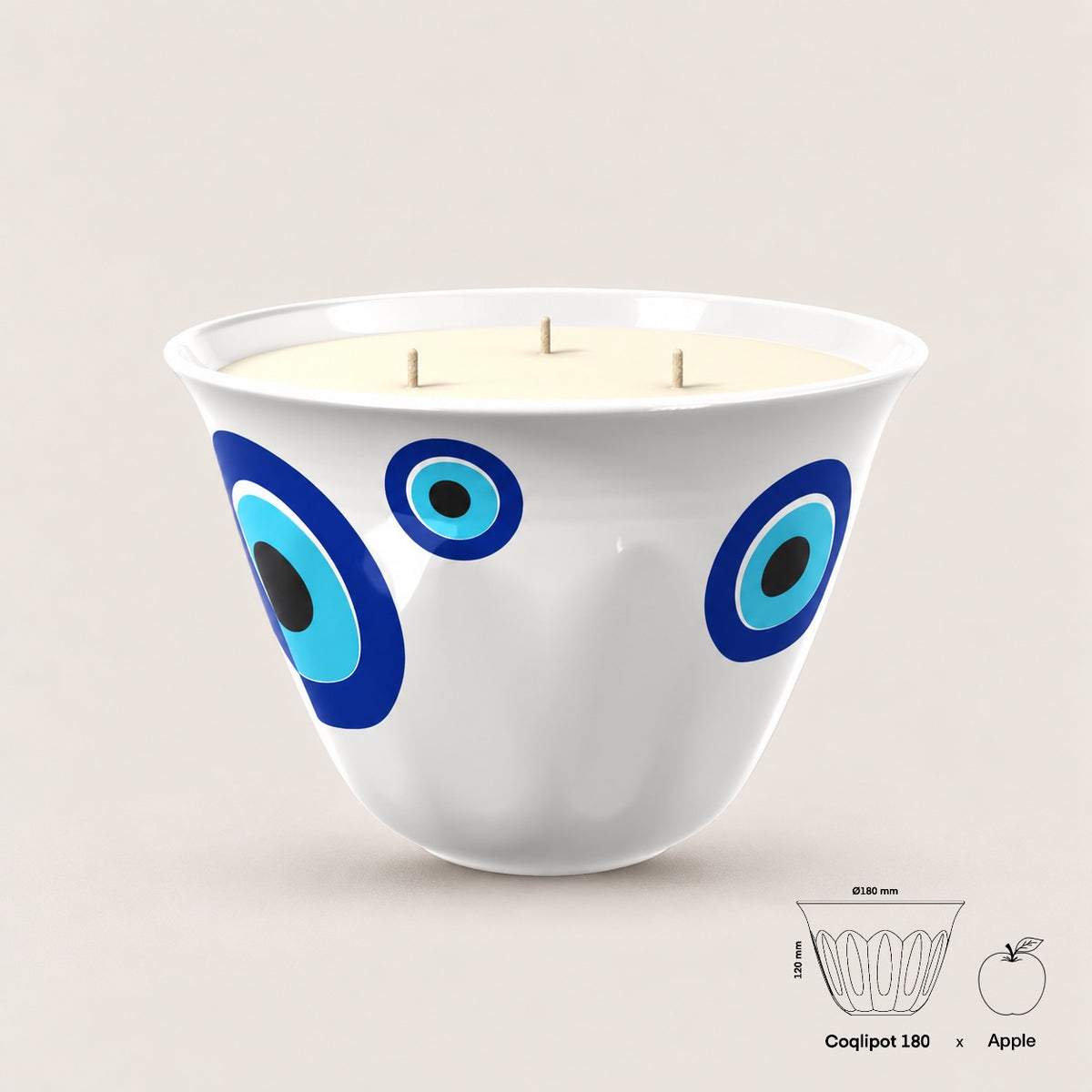 Coqlipot® 180 Kharzé Candle Edition — evil eye (Kharzé) ornament on a cement vessel, three-wick soy-blend wax candle, shown with apple for scale
